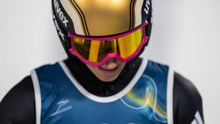 Katharina Schmid steht enttäuscht im Auslauf der Skisprungschanze und hält sich die Hände vor das Gesicht.