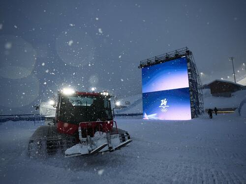 Eileen Gu mit Ski auf der Schulter im Schnee vor einer Halfpipe-Kulisse