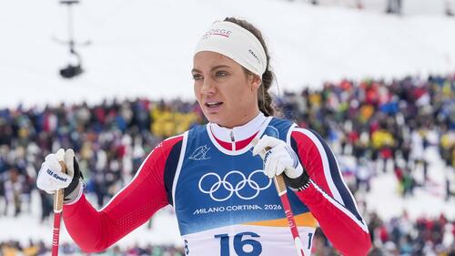 Kristine Stavas Skistad enttäuscht im Zielraum nach dem olympischen Sprint, während im Hintergrund schwedische Athletinnen jubeln