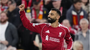 Jubelnder Harry Kane im Trikot des FC Bayern München und Mohamed Salah vom FC Liverpool auf dem Spielfeld.
