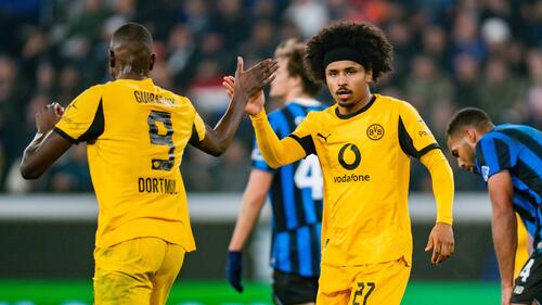 Karim Adeyemi und Serhou Guirassy im Trikot von Borussia Dortmund blicken nachdenklich auf das Spielfeld.