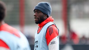 Alphonso Davies im Trikot des FC Bayern München blickt hochkonzentriert über das Spielfeld