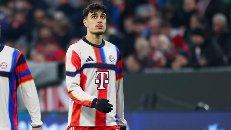 Aleksandar Pavlovic im Trikot des FC Bayern München blickt nachdenklich auf dem Spielfeld.