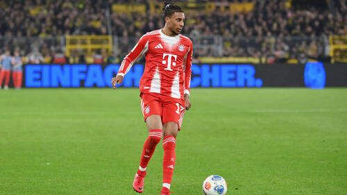 Michael Olise im Trikot des FC Bayern München führt den Ball im Spiel