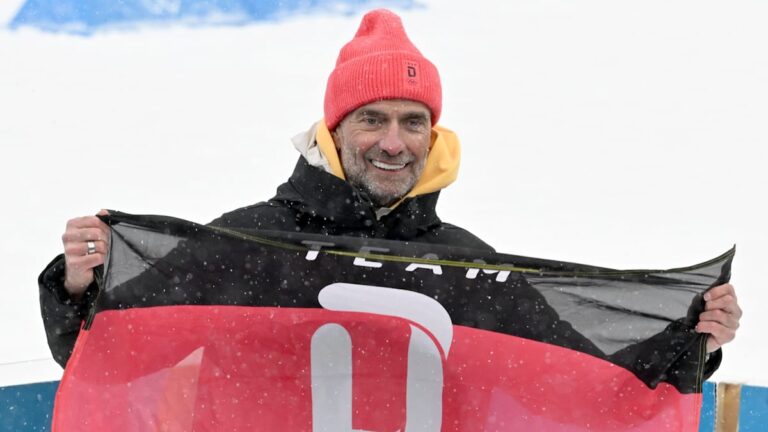 Jürgen Klopp lächelt entspannt und trägt ein sportliches Outfit vor einem unscharfen Hintergrund