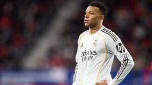 Kylian Mbappe sitzt frustriert und verletzt auf dem Rasen im Trikot von Real Madrid