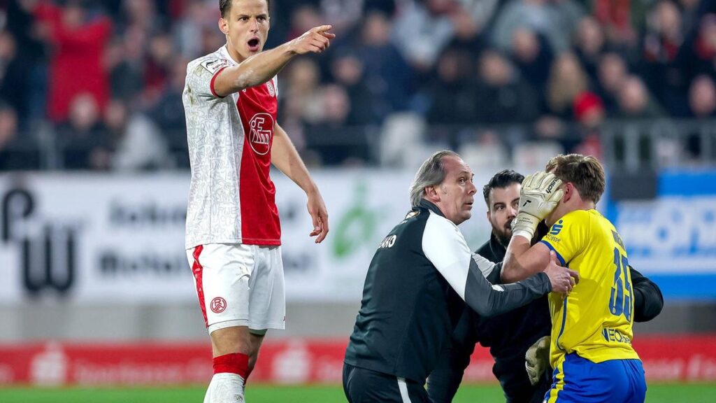 Schiedsrichter und Spieler stehen während der Unterbrechung im Stadion an der Hafenstraße auf dem Rasen