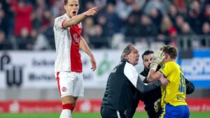 Schiedsrichter und Spieler stehen während der Unterbrechung im Stadion an der Hafenstraße auf dem Rasen