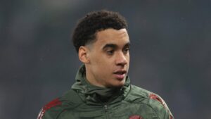 Jamal Musiala vom FC Bayern München sitzt enttäuscht auf dem Rasen, da er wegen einer Verletzung pausieren muss.