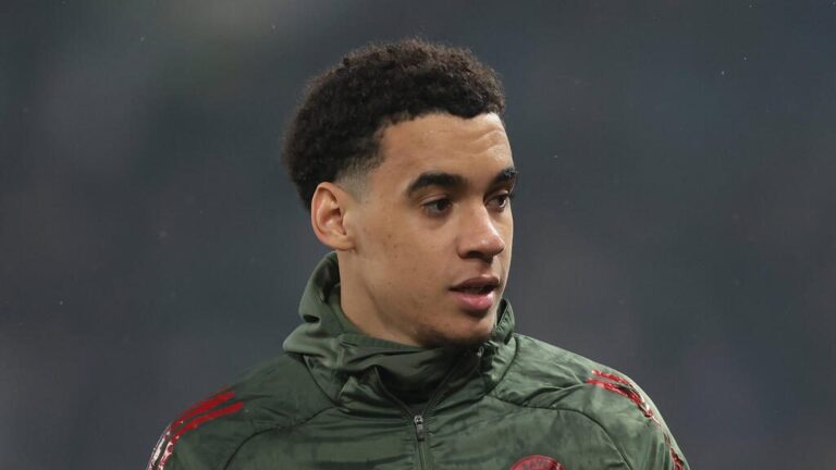 Jamal Musiala vom FC Bayern München sitzt enttäuscht auf dem Rasen, da er wegen einer Verletzung pausieren muss.