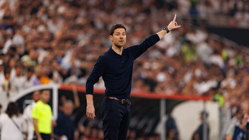 Xabi Alonso steht im Anzug an der Seitenlinie und gibt gestikulierend taktische Anweisungen