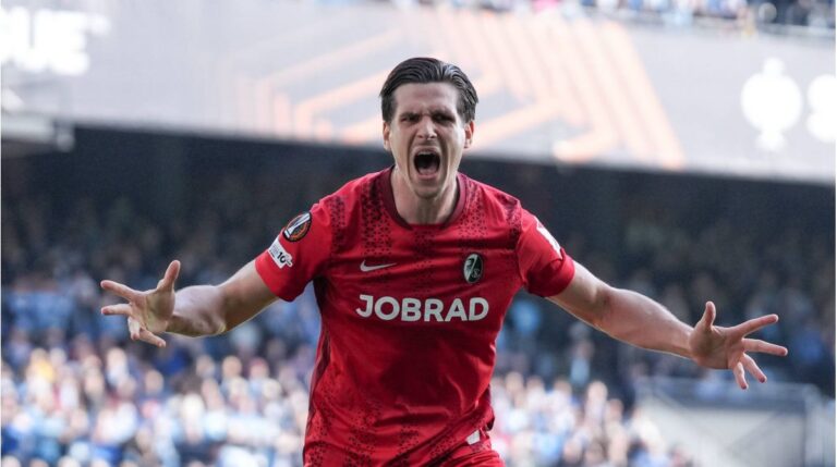 Spieler des FC Bayern München und SC Freiburg jubeln vor dem Logo der UEFA Champions League