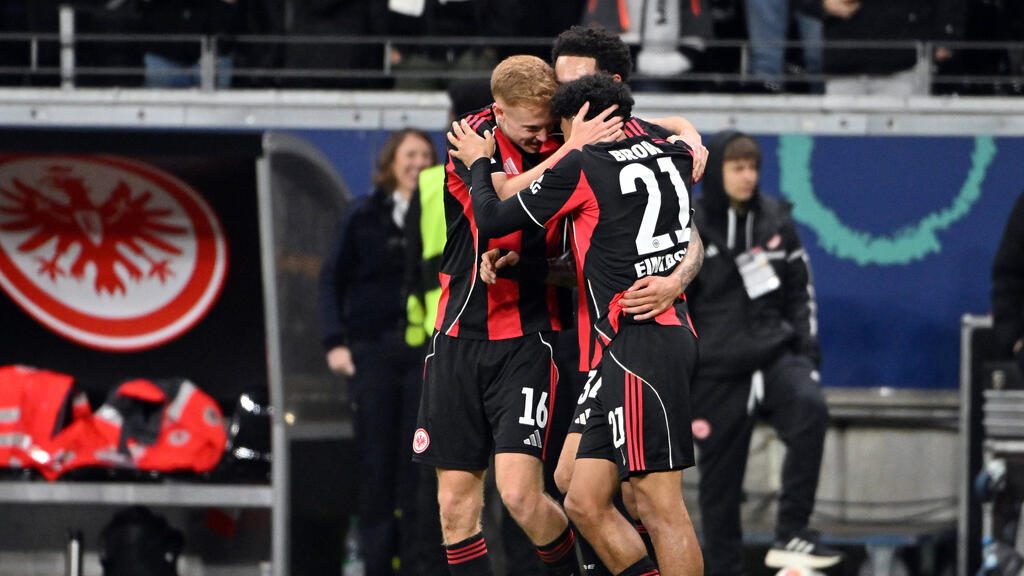 Spieler von Eintracht Frankfurt stehen auf dem Rasen vor der Fankurve im Stadion