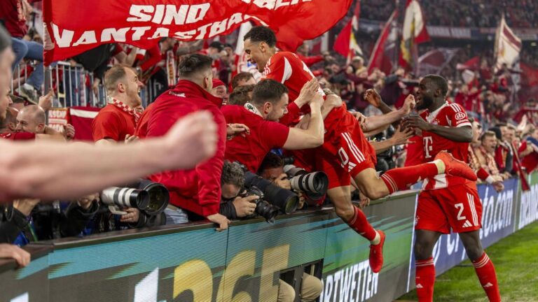 Fans des FC Bayern München jubeln mit Schals in der Allianz Arena vor der Südkurve