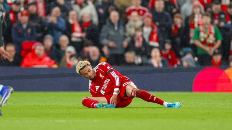 Hugo Ekitike vom FC Liverpool liegt verletzt am Boden und hält sich das Bein, während Betreuer zur Hilfe eilen.