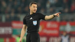 Schiedsrichter Felix Zwayer konzentriert mit Pfeife auf dem Fußballplatz