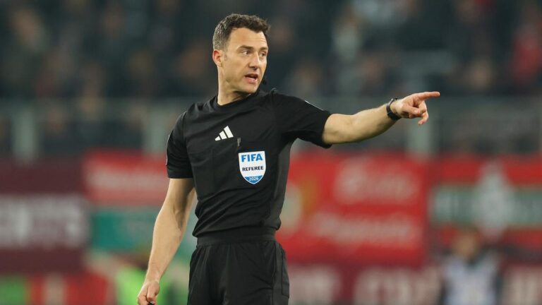 Schiedsrichter Felix Zwayer konzentriert mit Pfeife auf dem Fußballplatz