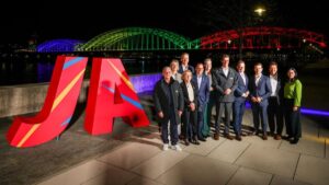 Jubelnde Menschen und Sportler vor dem Kölner Dom mit olympischen Ringen als Symbolbild für die Bewerbung KölnRheinRuhr.