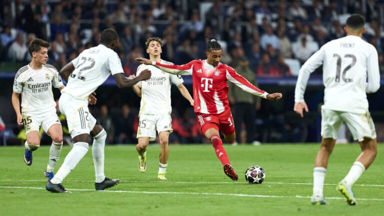 Michael Olise im Trikot des FC Bayern München dribbelt mit dem Ball auf dem Spielfeld.