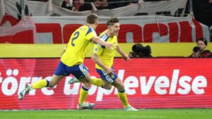 Robert Lewandowski winkt mit der Kapitänsbinde ins Publikum, schwedische Spieler jubeln im Hintergrund