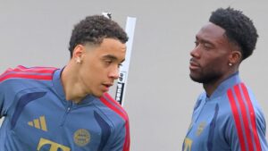 Alphonso Davies im Trikot des FC Bayern München fasst sich nach einer Verletzung enttäuscht an den Oberschenkel.