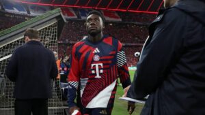 Alphonso Davies im Trikot der kanadischen Nationalmannschaft schaut nachdenklich auf das Spielfeld