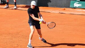 Jannik Sinner konzentriert sich auf seinen Aufschlag vor einem Match auf Sand.