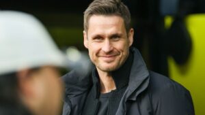 Sebastian Kehl steht lächelnd auf dem Rasen und wird von den BVB-Fans verabschiedet