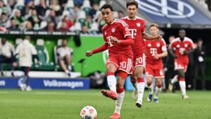 Jamal Musiala im Trikot des FC Bayern München dribbelt konzentriert mit dem Ball