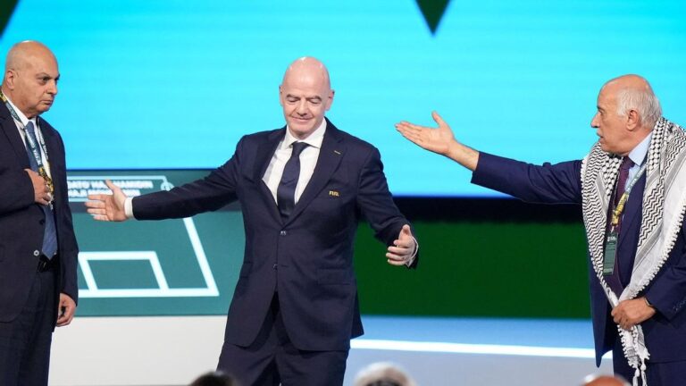 Gianni Infantino steht auf der Bühne zwischen Vertretern des israelischen und palästinensischen Verbands beim FIFA-Kongress