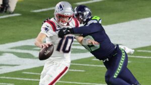 Ein Helm der Seattle Seahawks und das NFL-Logo vor einem vollbesetzten Football-Stadion bei Flutlicht