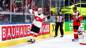 Jubelnde Eishockey-Spieler der Schweizer Nationalmannschaft im roten Trikot auf dem Eis
