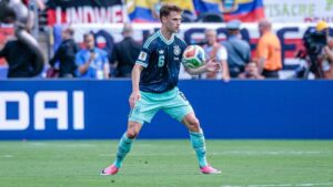 Joshua Kimmich im Trikot der deutschen Nationalmannschaft mit nachdenklichem Blick, im Hintergrund Julian Nagelsmann.