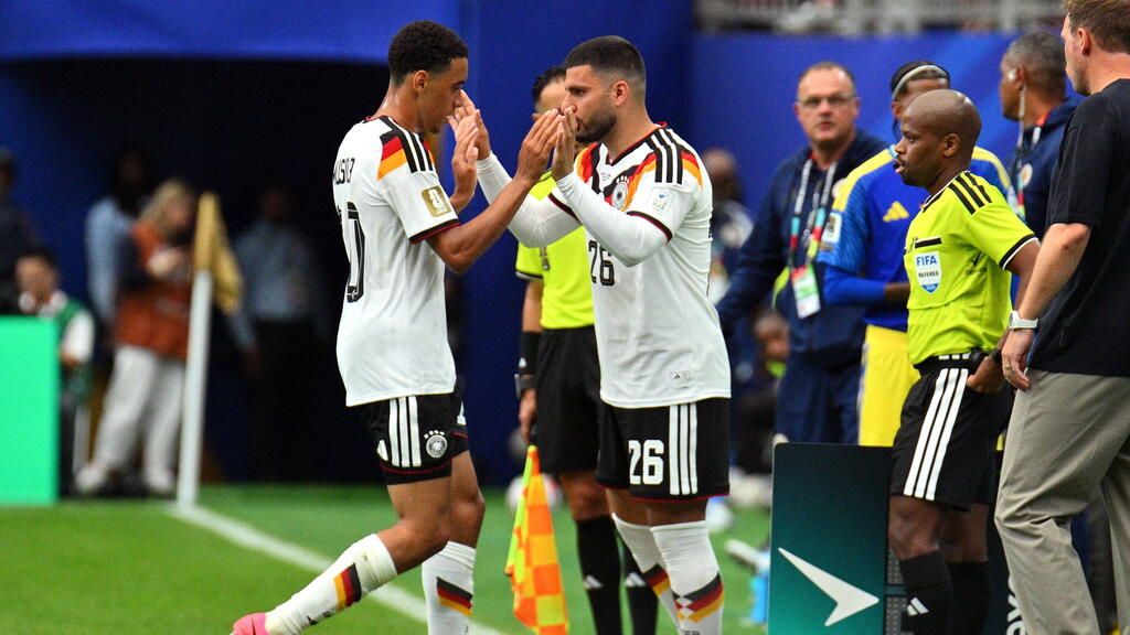 Deniz Undav jubelt im DFB-Trikot, während Jamal Musiala nachdenklich auf der Ersatzbank sitzt.