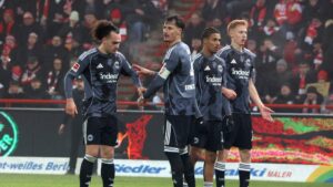 Die Eintracht-Profis Hugo Larsson und Arthur Theate stehen im Trikot von Frankfurt auf dem Spielfeld