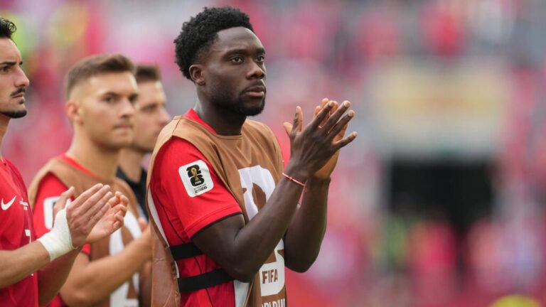 Alphonso Davies im Trikot des FC Bayern München blickt nachdenklich und enttäuscht auf das Spielfeld.