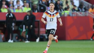 Florian Wirtz am Ball in der Premier League, während Xabi Alonso das Spiel an der Seitenlinie beobachtet.