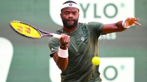 Frances Tiafoe jubelt mit dem Siegerpokal der Terra Wortmann Open in Halle auf dem Rasenplatz.
