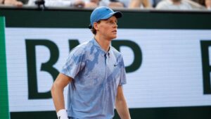 Tennisprofi Jannik Sinner hochkonzentriert beim Aufschlag auf dem Rasenplatz in Wimbledon.