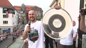 Handballer des SC Magdeburg präsentieren die Meisterschale jubelnd auf dem Rathausbalkon vor tausenden Fans