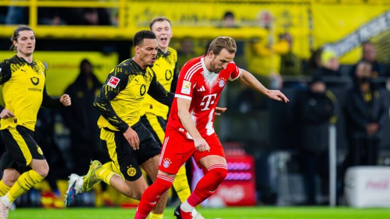 Die Wappen von Borussia Dortmund und Bayern München vor dem Hintergrund eines Fußballstadions