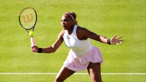 Serena Williams schlägt auf dem Rasenplatz in Wimbledon in weißer Spielkleidung den Ball