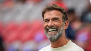 Jürgen Klopp lächelt am Spielfeldrand und winkt den Fans zu