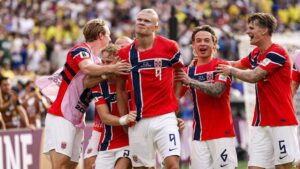 Erling Haaland im Trikot von Manchester City blickt fokussiert auf das Spielfeld.