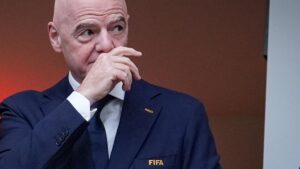 FIFA-Präsident Gianni Infantino blickt mit ernster Miene vor einem Hintergrund der olympischen Ringe.
