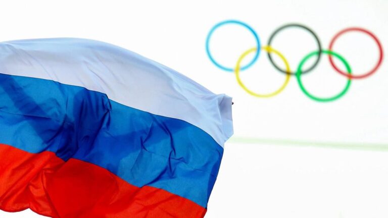 Die olympischen Ringe am Hauptquartier des IOC in Lausanne neben einer russischen Flagge