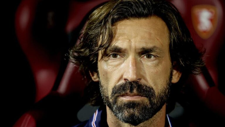 Andrea Pirlo im Anzug schaut nachdenklich, im Hintergrund das Logo der italienischen Nationalmannschaft