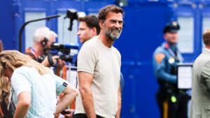 Arsène Wenger blickt nachdenklich, während Jürgen Klopp im Hintergrund als künftiger DFB-Bundestrainer zu sehen ist.