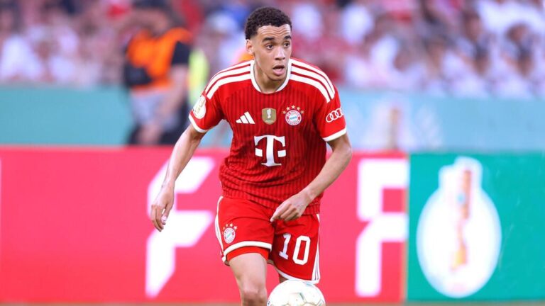 Jamal Musiala im Trikot des FC Bayern München blickt nachdenklich auf das Spielfeld