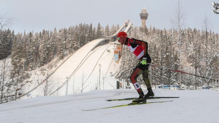 Ein enttäuschter Athlet der Nordischen Kombination im Schnee nach einem Wettkampf